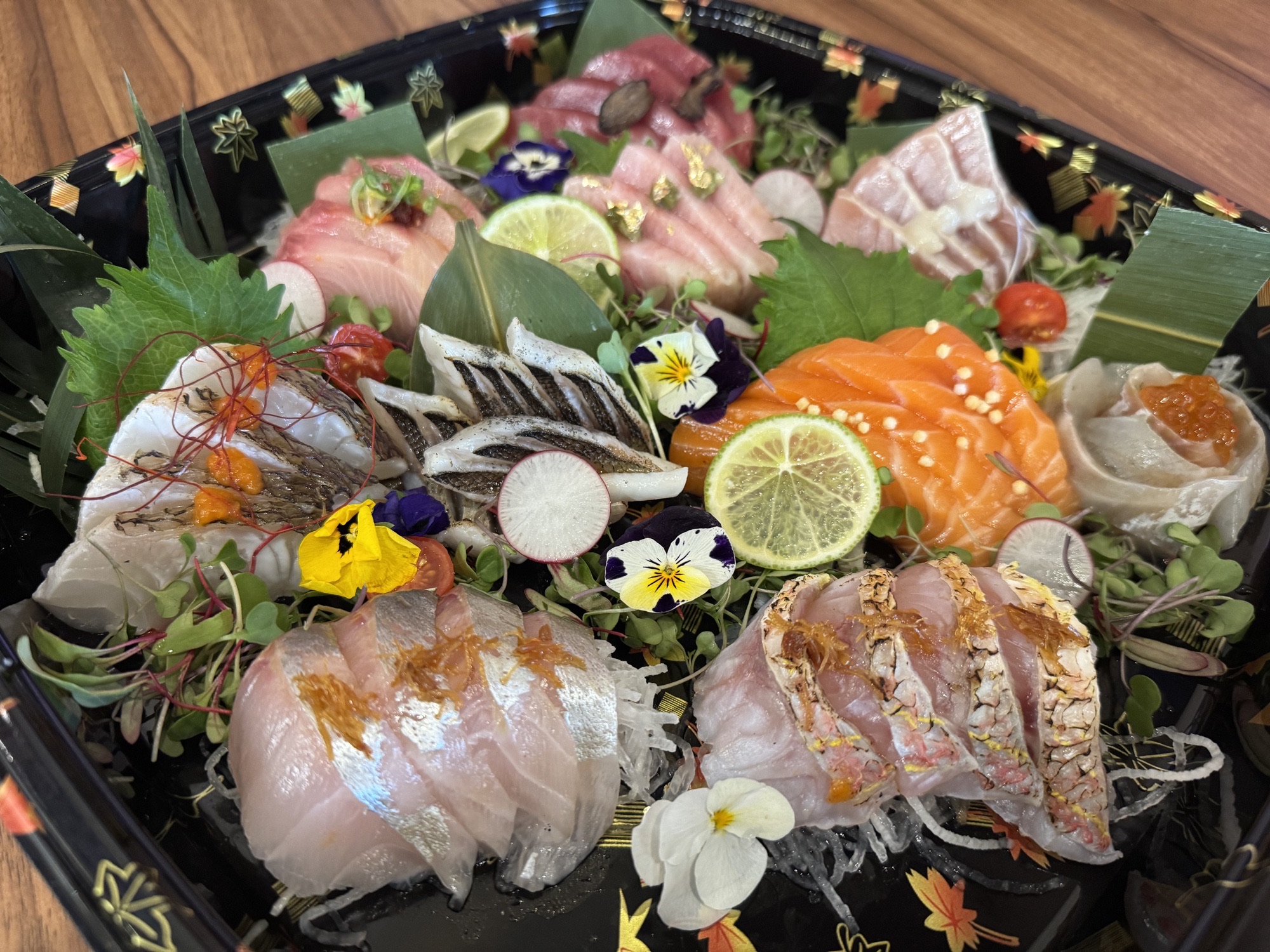 An abundant Shoya sashimi platter with salmon, tuna, citrus and edible flowers